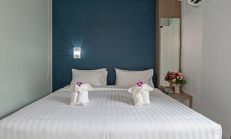 Una habitación de hotel con una cama grande, ropa de cama blanca y una pared de acento azul.