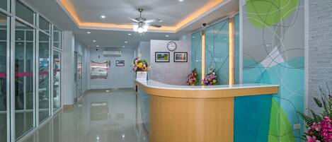 A reception area with a curved reception desk, a ceiling fan, and a clock on the wall.