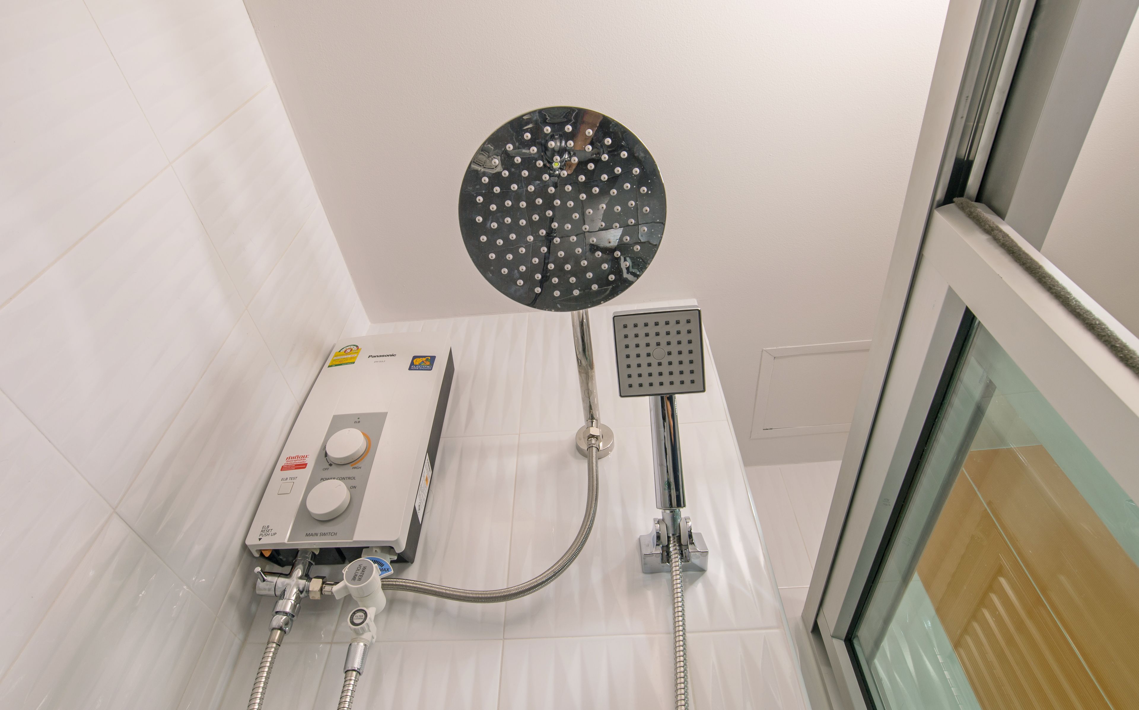 A modern bathroom with a handheld showerhead, a built-in control panel, and a glass shower enclosure.