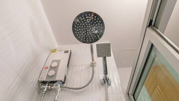 A modern bathroom with a handheld showerhead, a built-in control panel, and a glass shower enclosure.