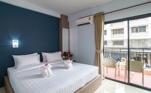 Une chambre d’hôtel avec un grand lit, une fenêtre donnant sur l’extérieur, un appareil de climatisation et un luminaire fixé au mur.