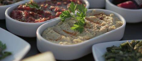 A variety of dishes in white bowls, including a hummus topped with parsley.