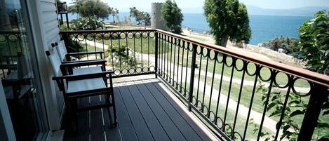 A balcony with a view of the sea, a stone tower, and a wooden deck.