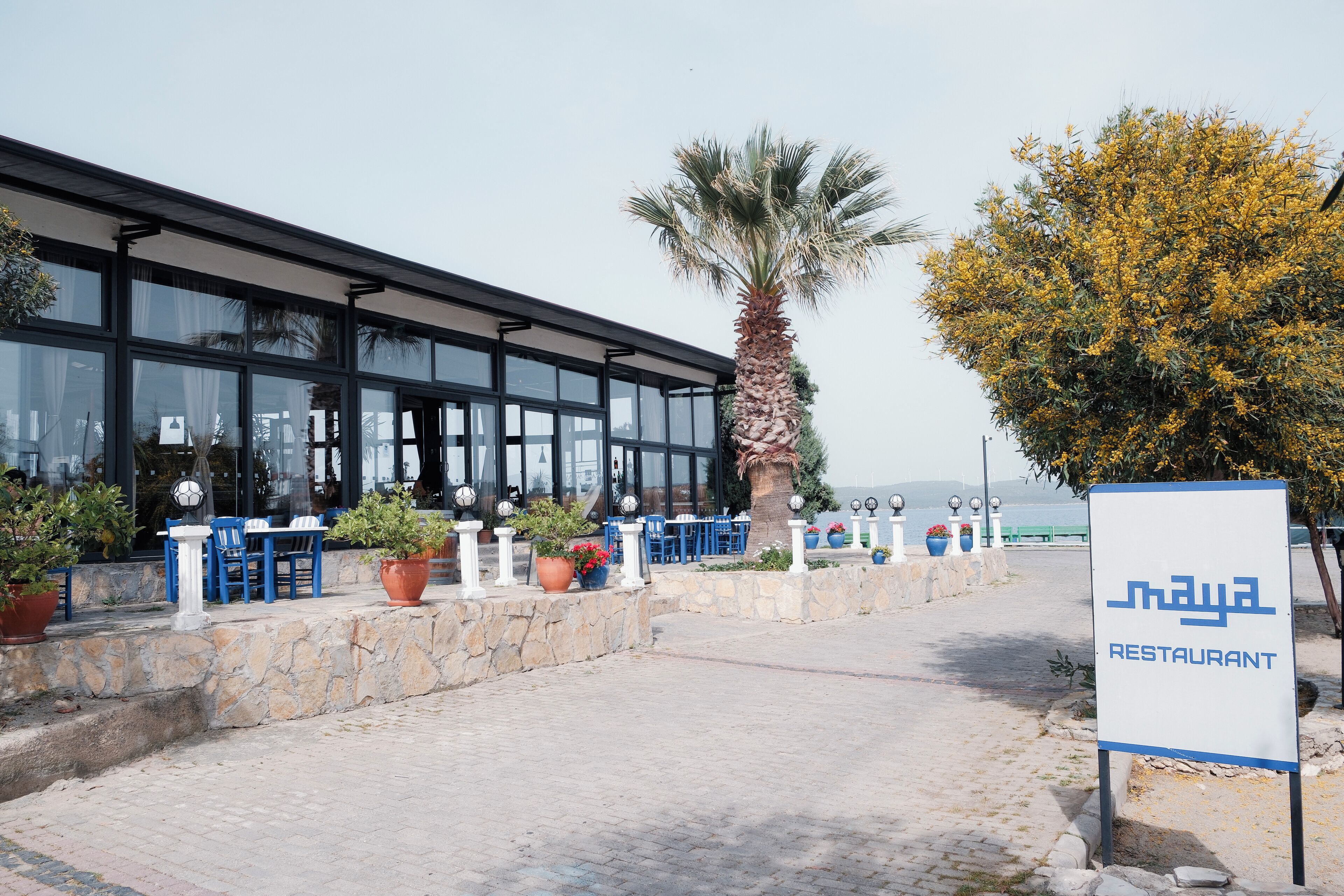 A restaurant with outdoor seating, stone walls, and potted plants.