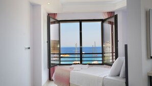 Une chambre avec une grande fenêtre donnant sur la mer et les bateaux.