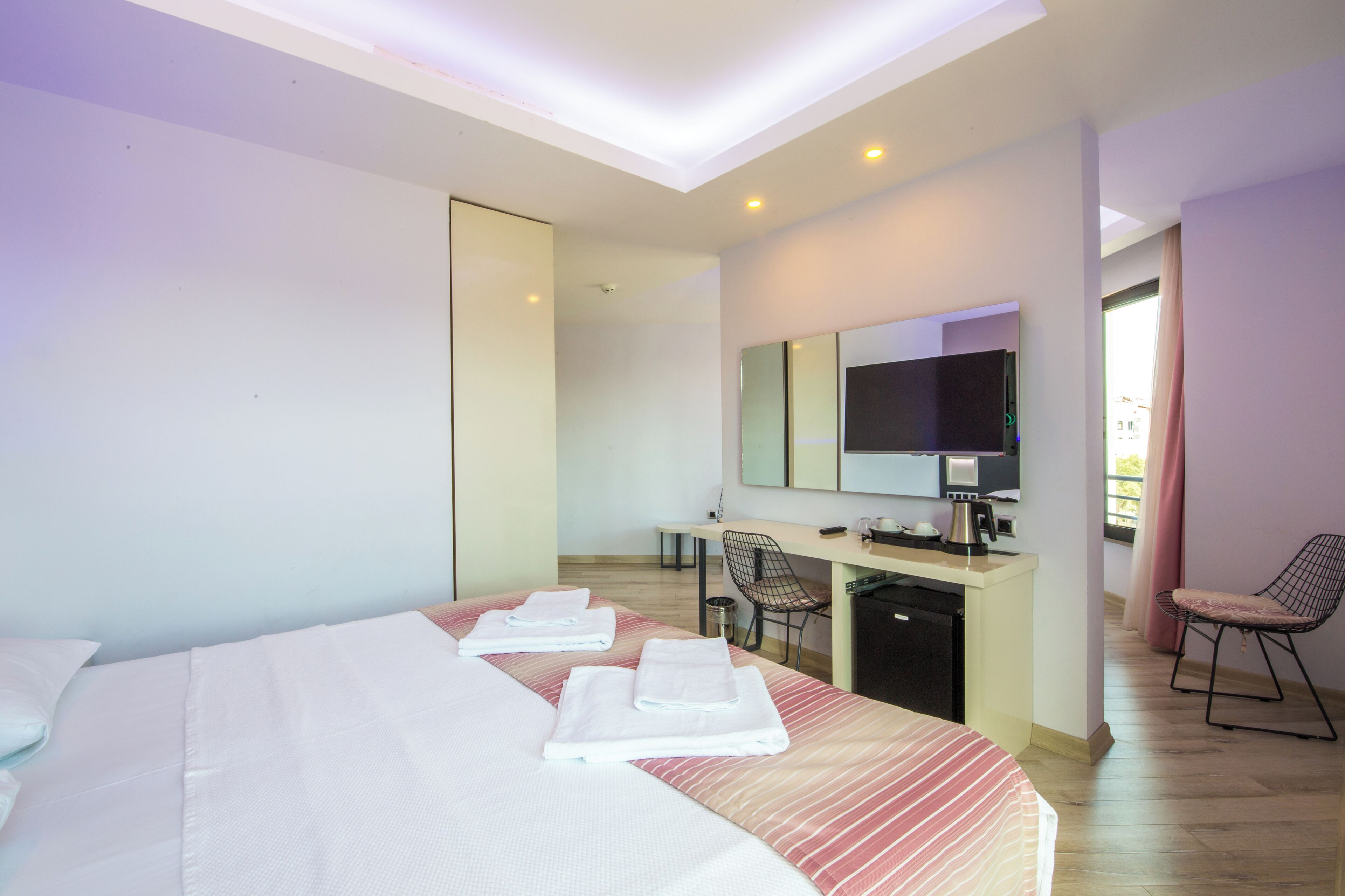 Une chambre d’hôtel comprenant un lit, un bureau avec un ordinateur, une chaise et un téléviseur.