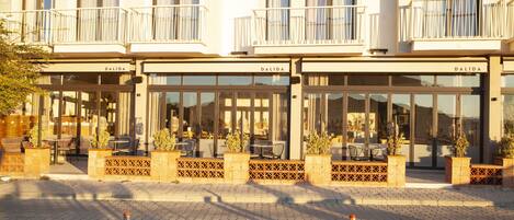 Un hotel con varios balcones, mobiliario exterior y plantas en macetas.