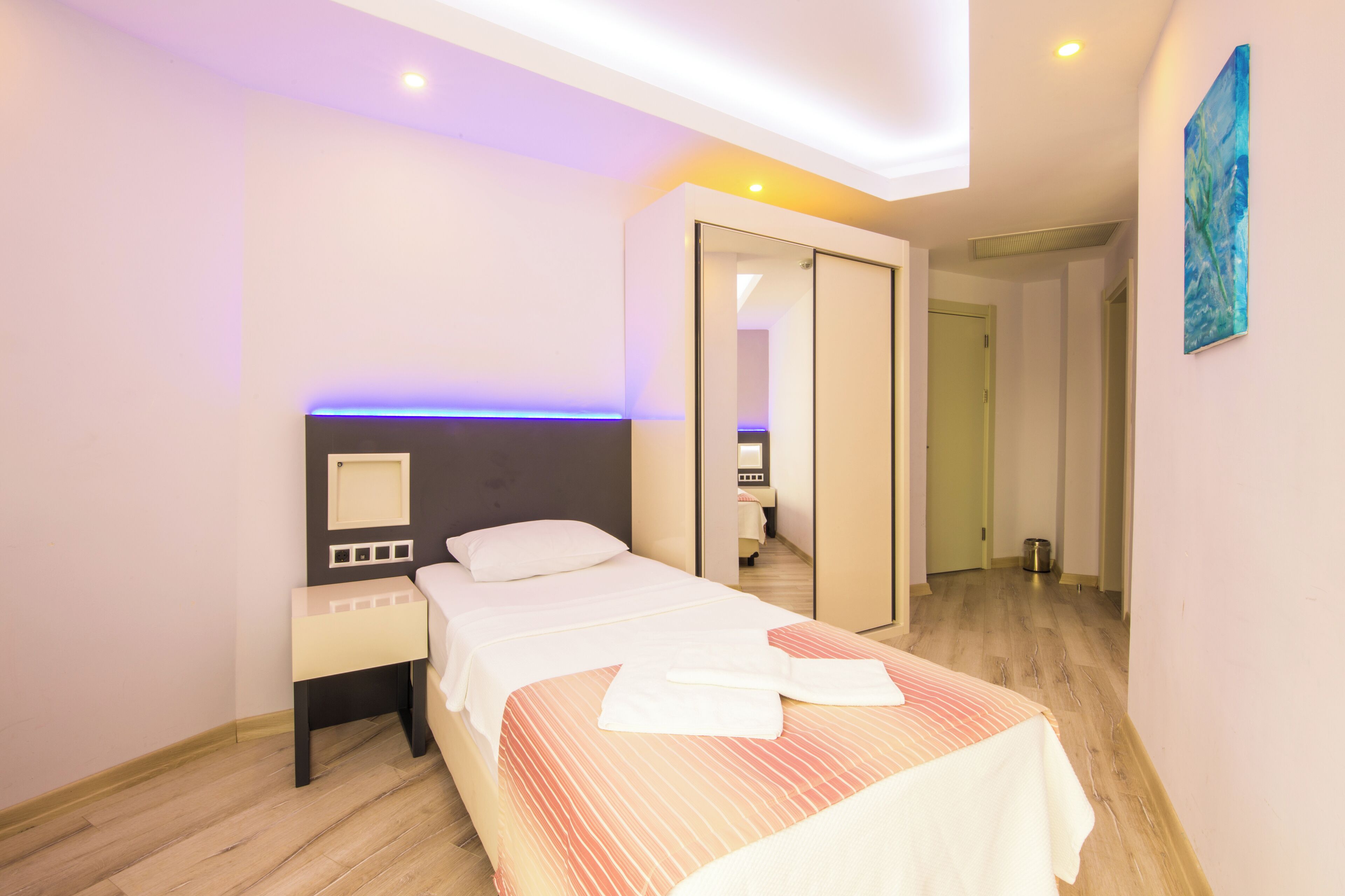 A modern hotel room with a bed, bedside table, and a mirror.