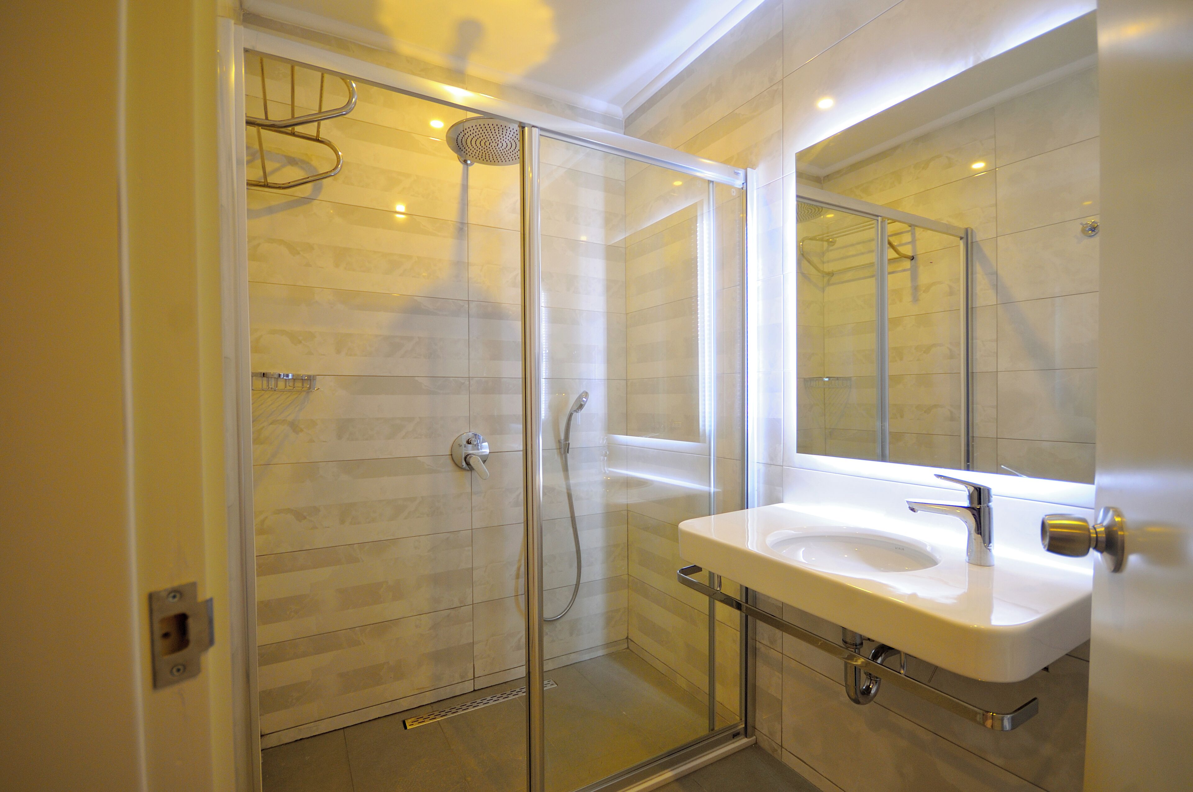 A modern bathroom with a glass-enclosed shower, a white sink, and a large mirror.