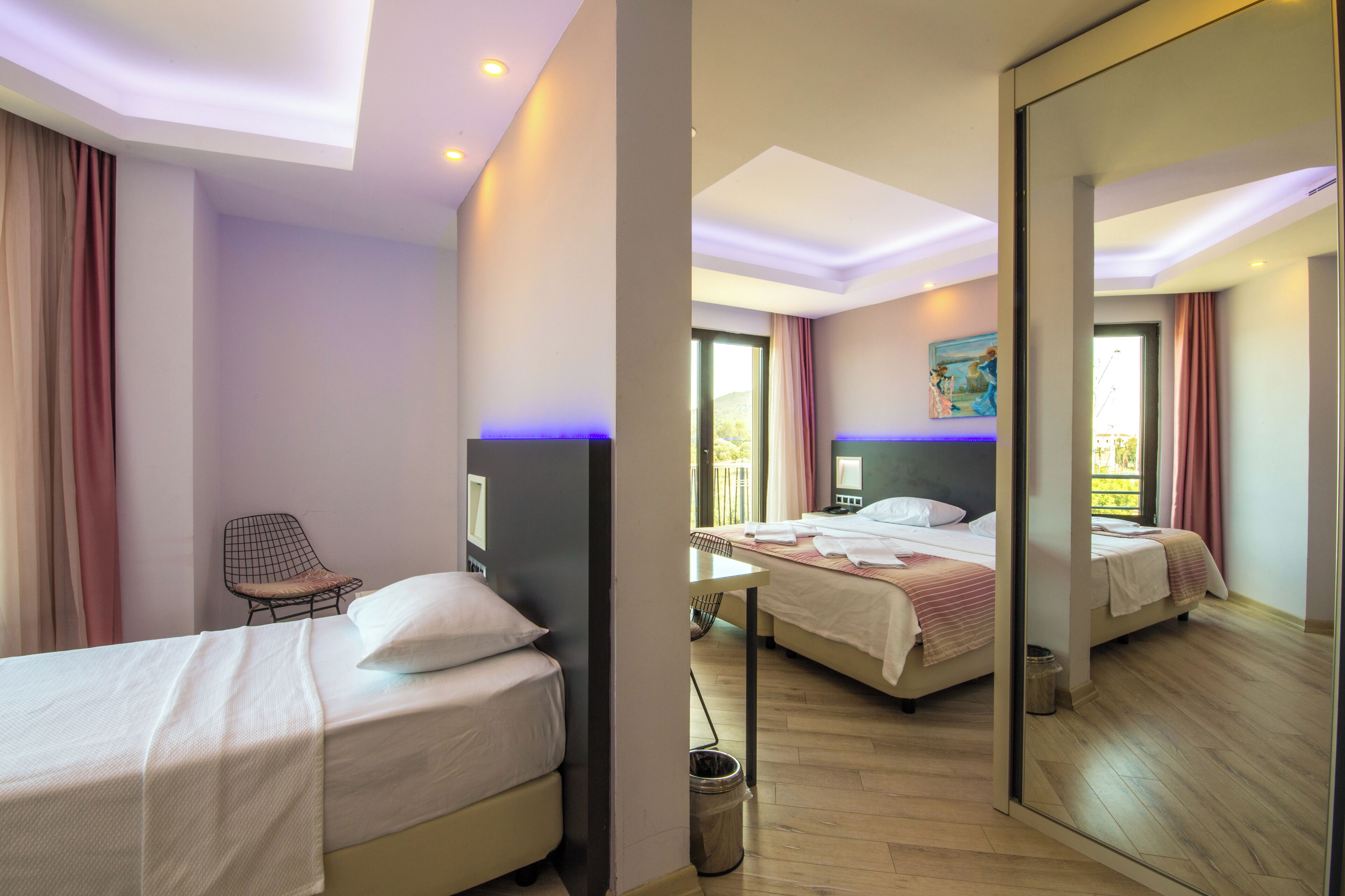 A hotel room with two beds, a chair, a desk, and a large mirror.