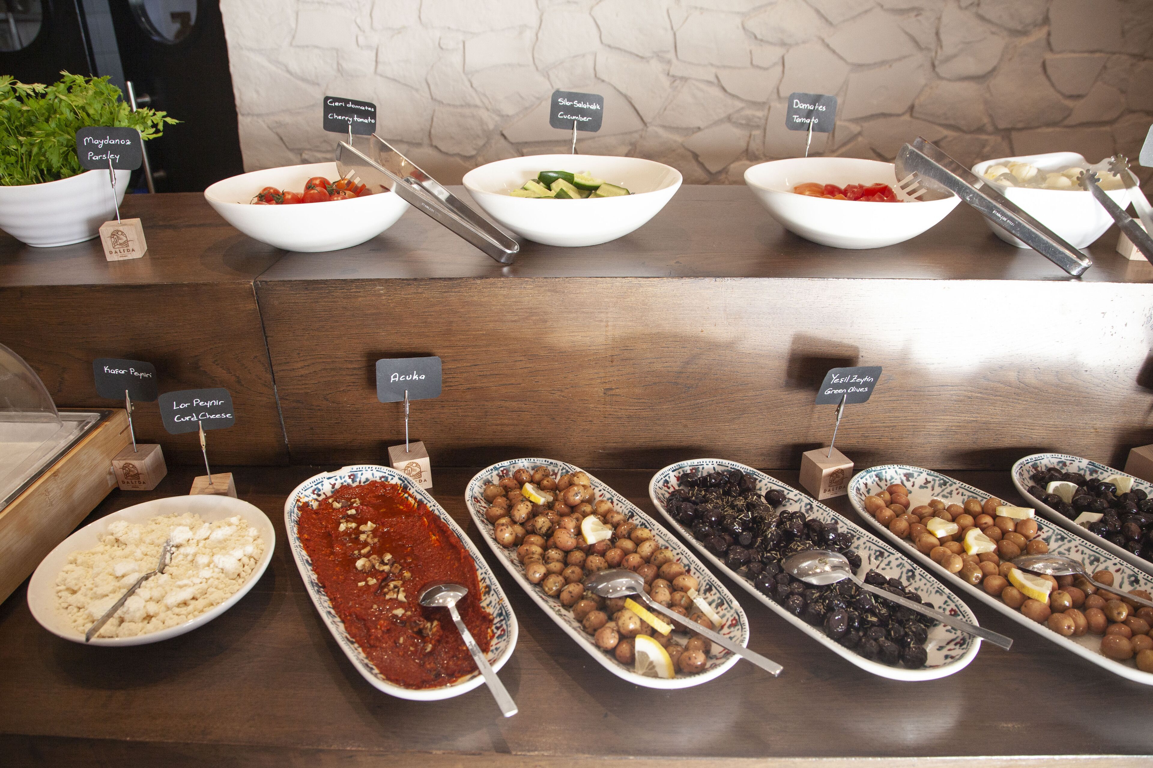 A buffet with various food options including salads, cheeses, and olives.