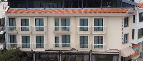 A multi-story hotel with balconies, a ground-level cafe, and a visible restaurant.