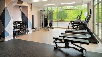 A gym with treadmills, dumbbells, and weight machines.