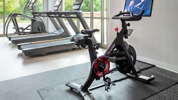 Un gimnasio interior con bicicletas estáticas, cintas de correr y un ventanal amplio.