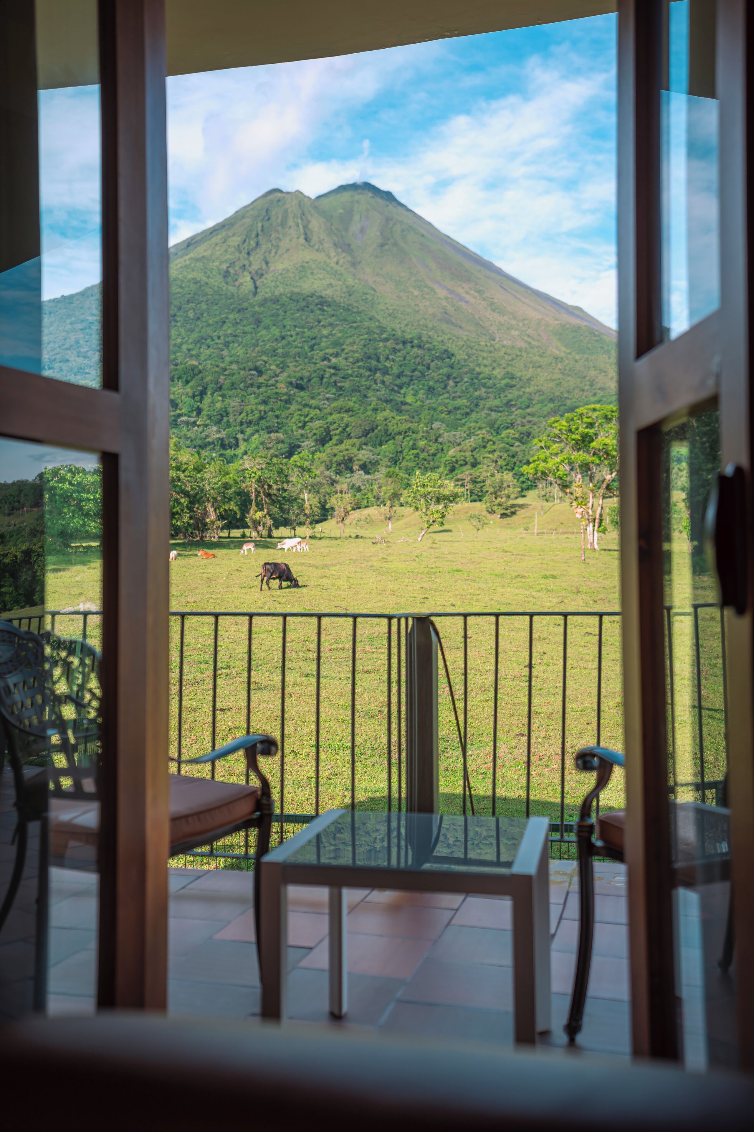 Un balcón con vista a un campo cubierto de césped y una montaña.