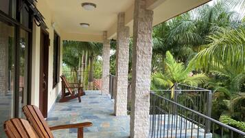 Relax on the balcony with a view of lush greenery, featuring a seating area with two chairs and a table.