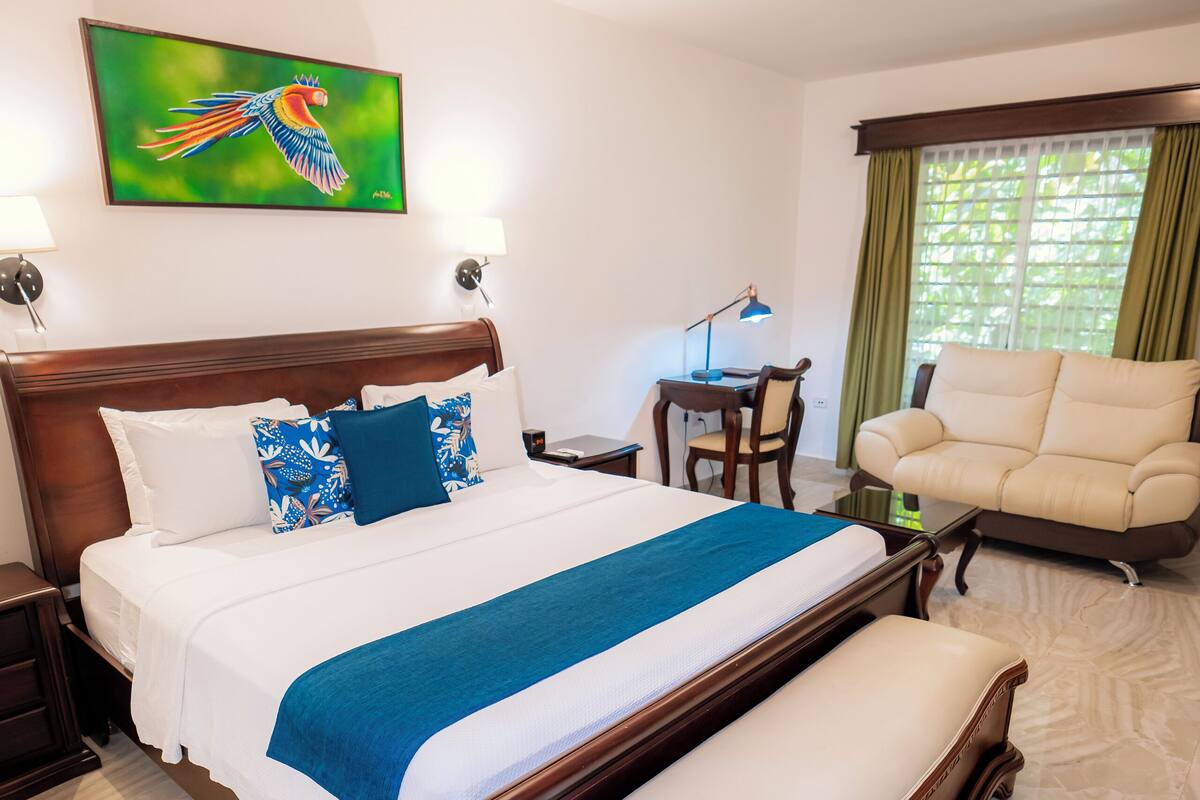 Une chambre d’hôtel avec un grand lit, un bureau, une chaise et un canapé.