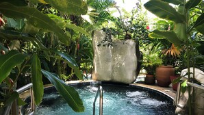 Un bain à remous entouré d’une végétation luxuriante et de plantes en pot.