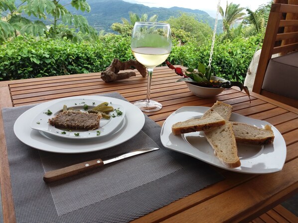 A table with a plate of food, a glass of white wine, and a knife.