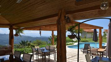 An outdoor patio with a pool, wooden furniture, and a view of mountains.