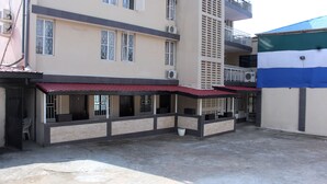 Un immeuble à plusieurs étages, doté d’une façade sobre, de grandes fenêtres et d’un auvent rouge au-dessus de l’entrée.