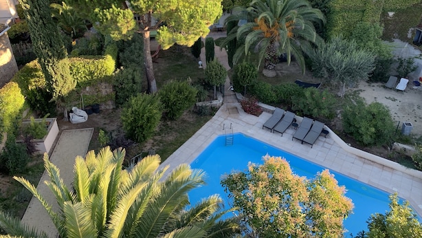A residential area with a swimming pool surrounded by lush greenery and a few lounge chairs. - Le Jardin D'homps (Homps)