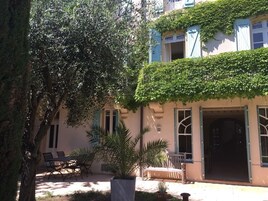 A building with a covered patio area, outdoor seating, and a large tree.