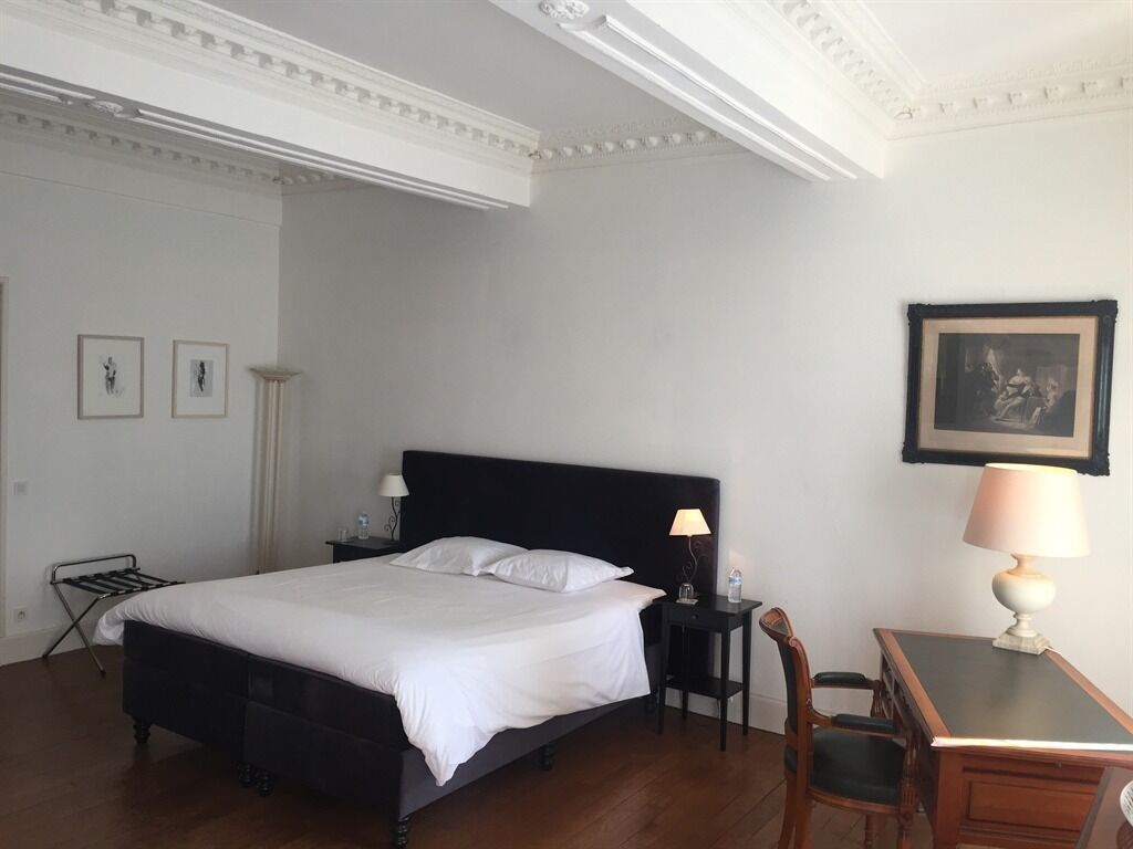 Een hotelkamer met een groot bed, een nachtkastje, een bureau en een stoel.
