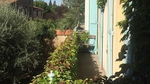 A narrow alleyway with a building on one side and a tree-lined path on the other. - Le Jardin D'homps (Homps)