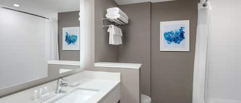A modern bathroom with a large mirror, a sink, a toilet, and a shower.