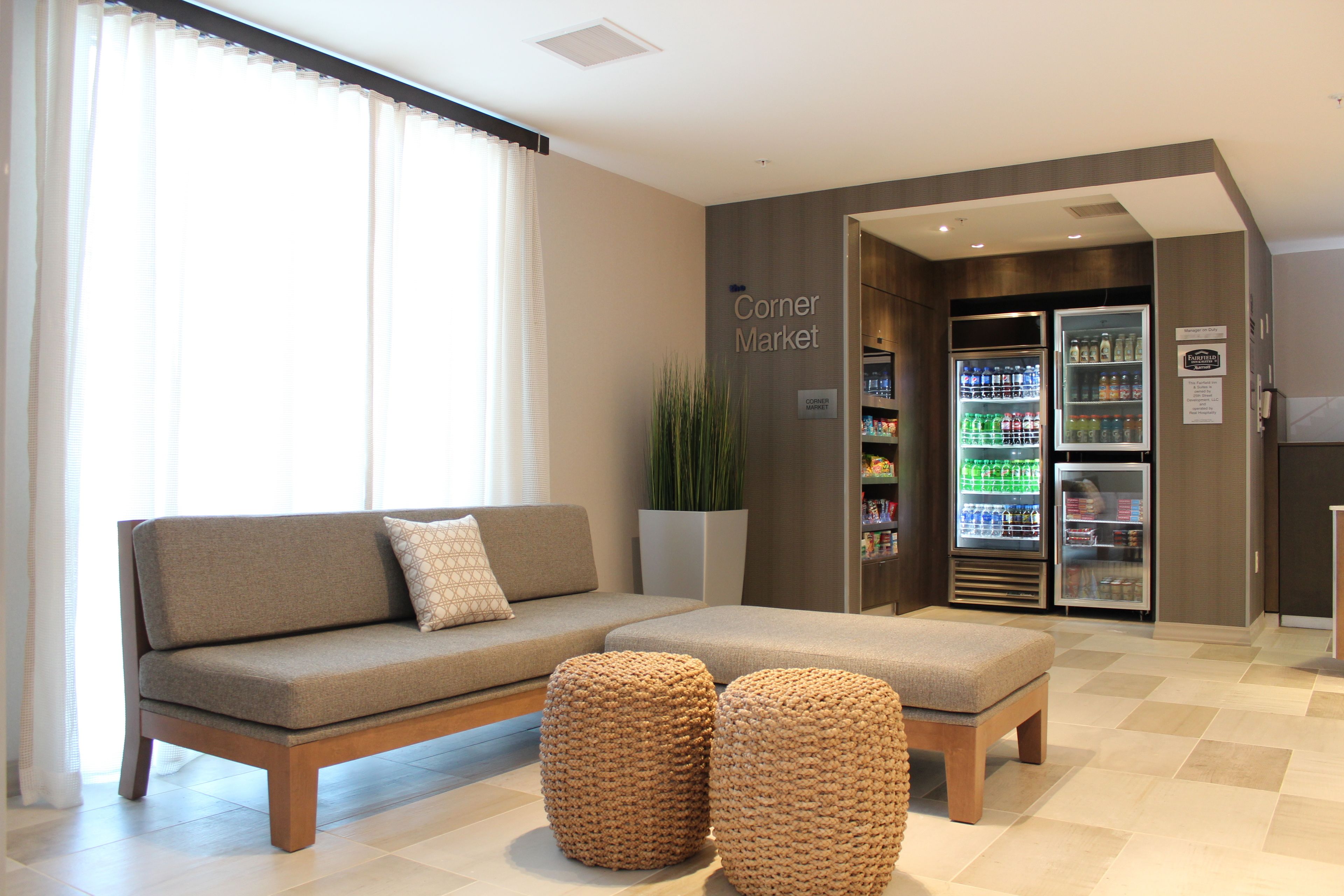 Eine moderne Hotelhalle mit einer Couch, Hocker und einem Kiosk mit gekühlten Getränken.