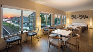 Un espace repas doté de grandes fenêtres, d’un plancher en bois et de meubles modernes.