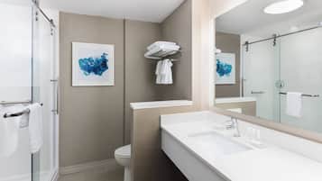 Un baño moderno con cabina de ducha de vidrio, un lavabo blanco y un espejo grande.
