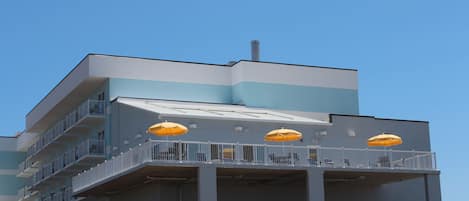 A multi-story building with balconies, some with yellow umbrellas.