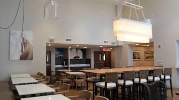 A restaurant with multiple tables and chairs, a large hanging light fixture, and artwork on the walls.
