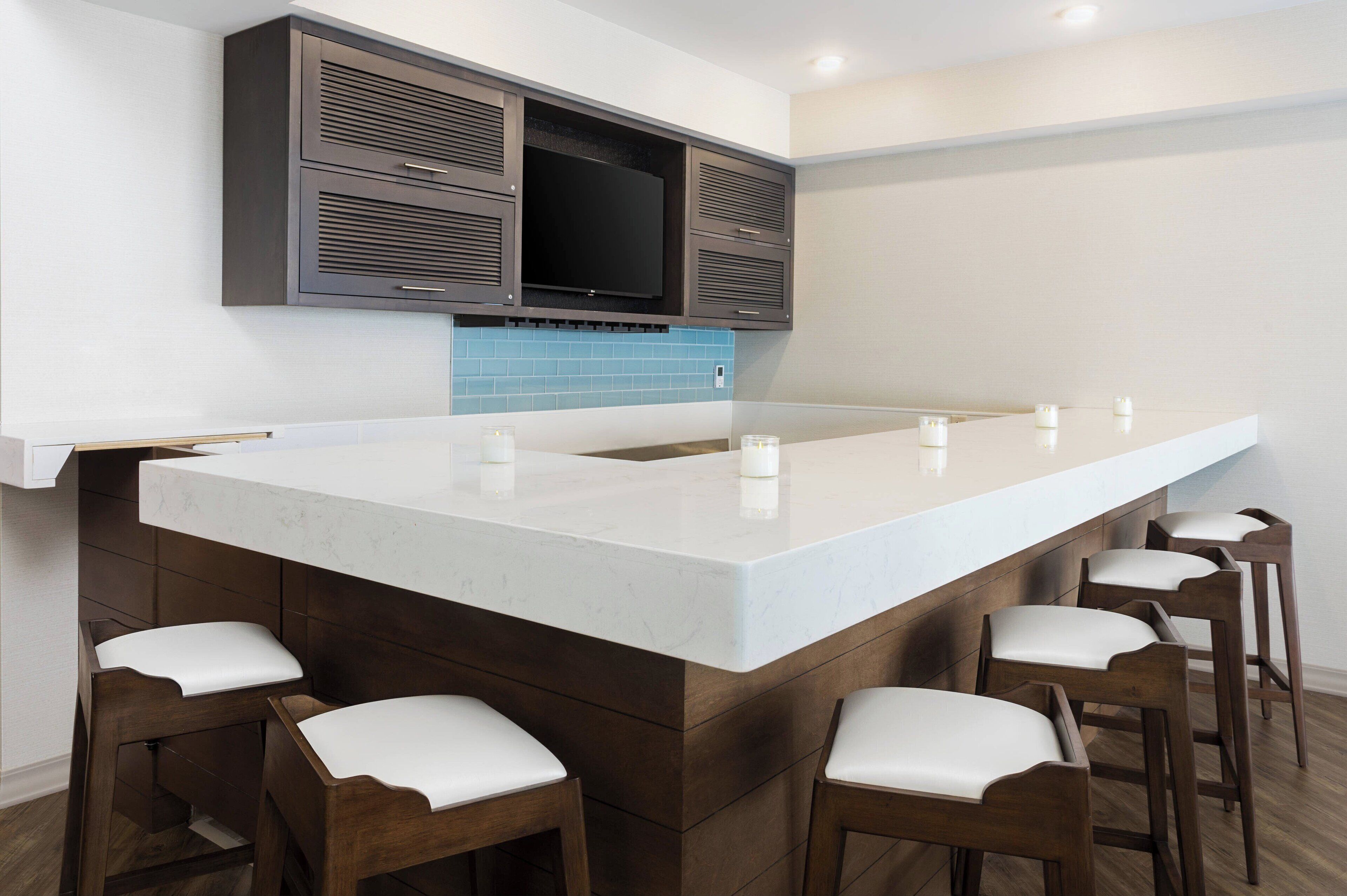Una cocina moderna con una isla grande, armarios de madera oscura y un televisor de pantalla plana montado sobre la isla.