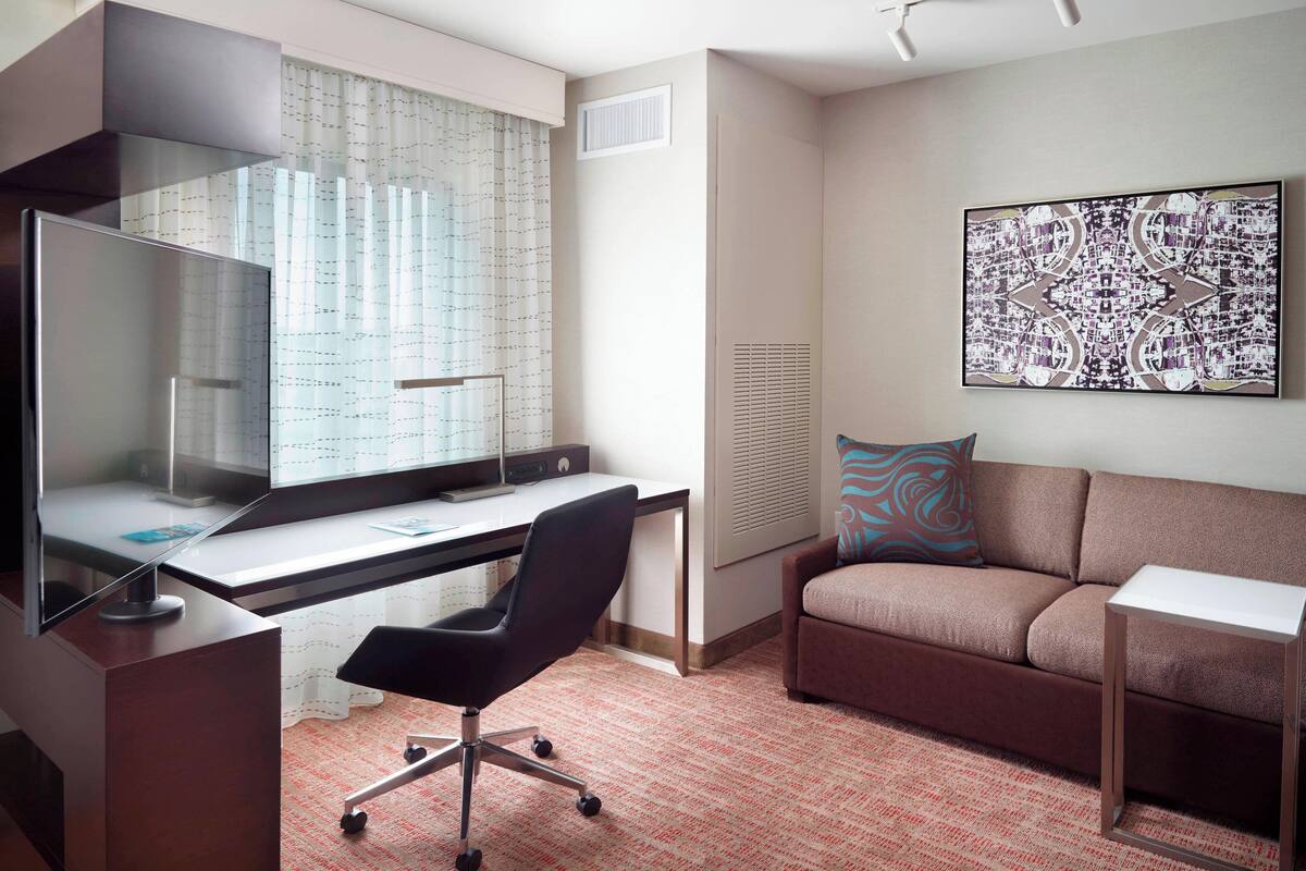 A modern office space with a desk, chair, and a sofa.