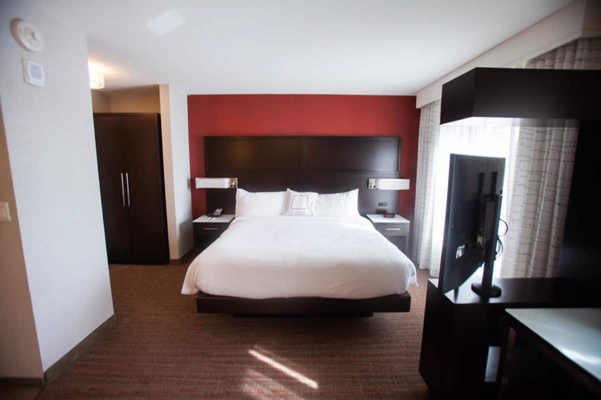 A hotel room with a large bed, a TV, a desk, and a wardrobe.