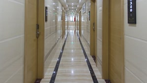 A long, well-lit hallway with marble flooring and wooden doors, leading to multiple rooms. - Jiamei Hotel (Guangzhou)