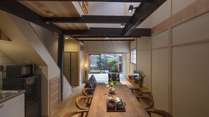 A modern kitchen with a wooden dining table, black appliances, and a view to a garden. - Shimabara Kaiden (Kyoto)