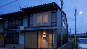 A traditional Japanese house with a sliding door, a small porch, and a car parked outside. - Shimabara Kaiden (Kyoto)