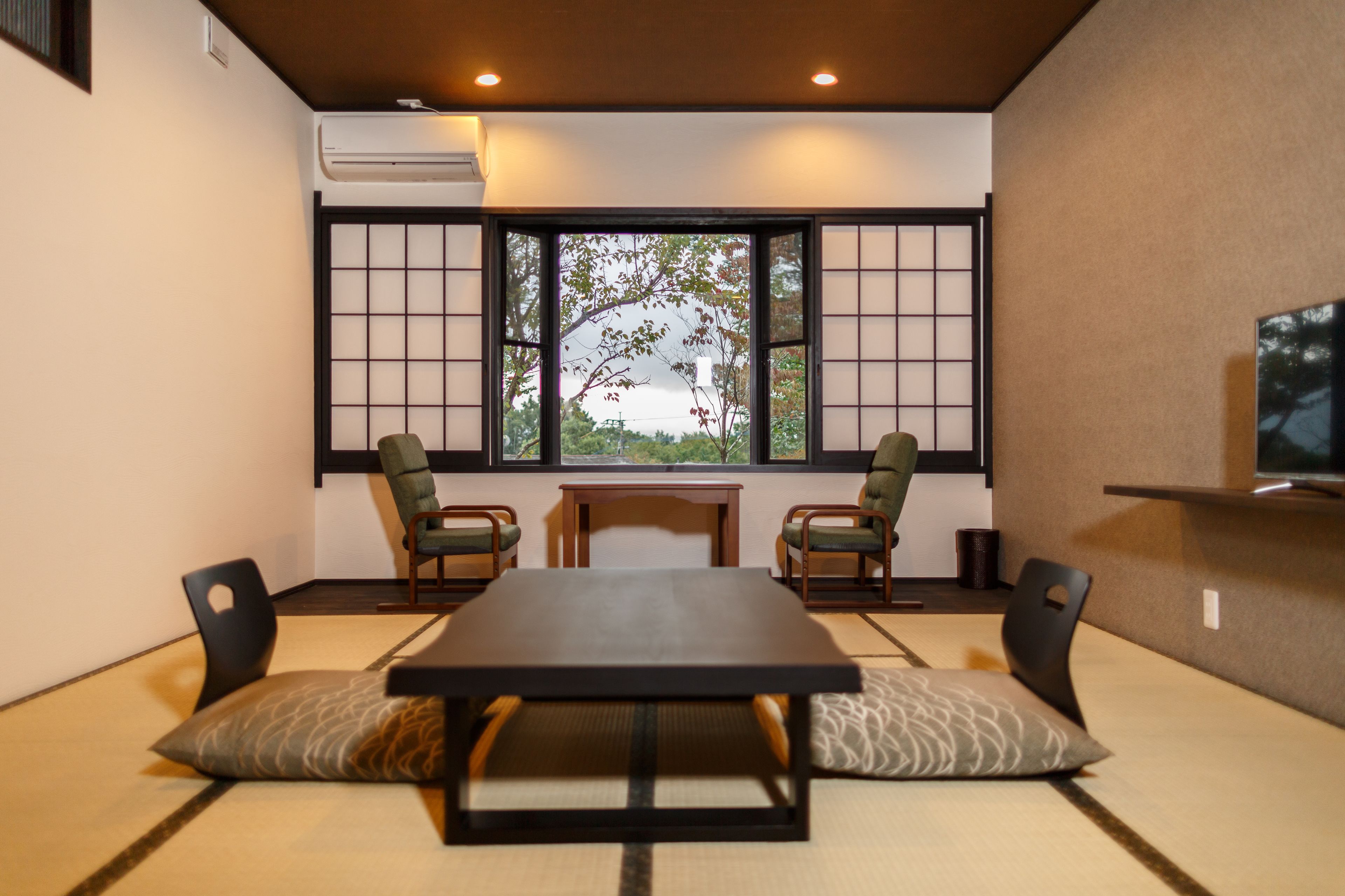 Una habitación tradicional japonesa con suelo de tatami, una mesita baja y dos sillas.