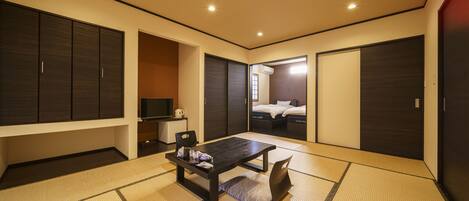 A modern hotel room with a tatami mat floor, a dark wooden table, and a bed with a white headboard.