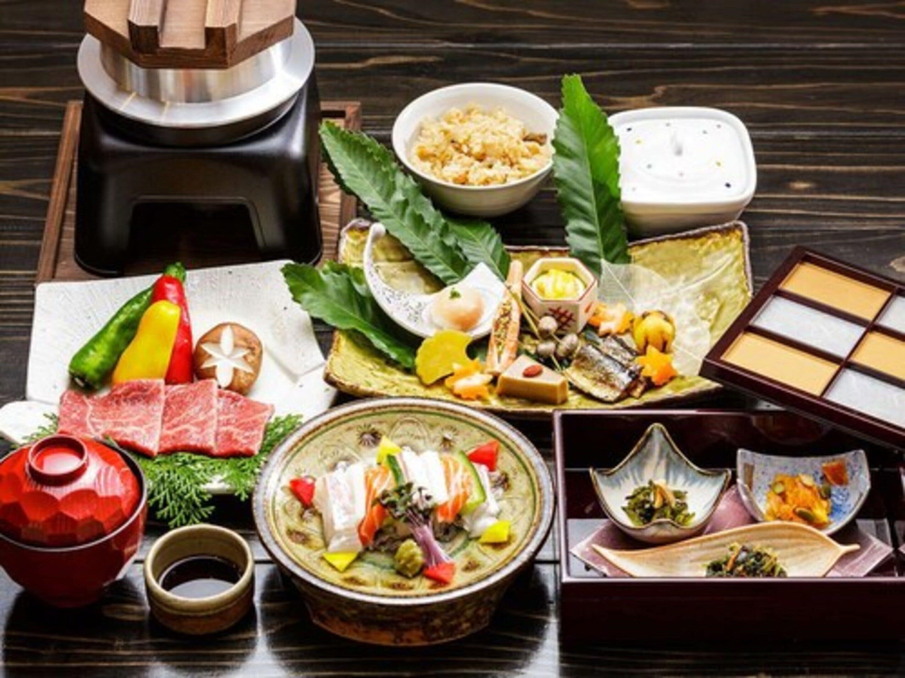 A variety of Japanese dishes including sashimi, sushi, and tempura, arranged on a wooden table.