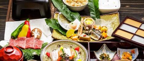 A variety of Japanese dishes including sashimi, sushi, and tempura, arranged on a wooden table.