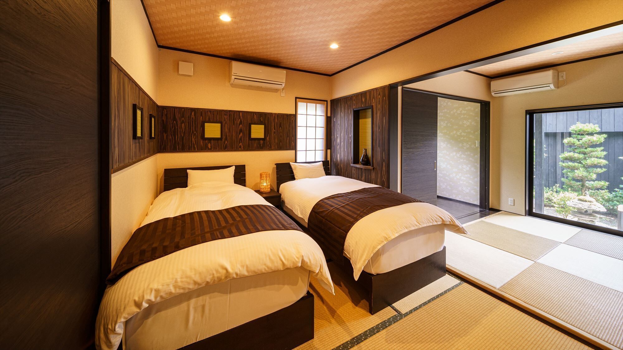 A hotel room with two beds, a sliding door to a balcony, and a traditional Japanese aesthetic.