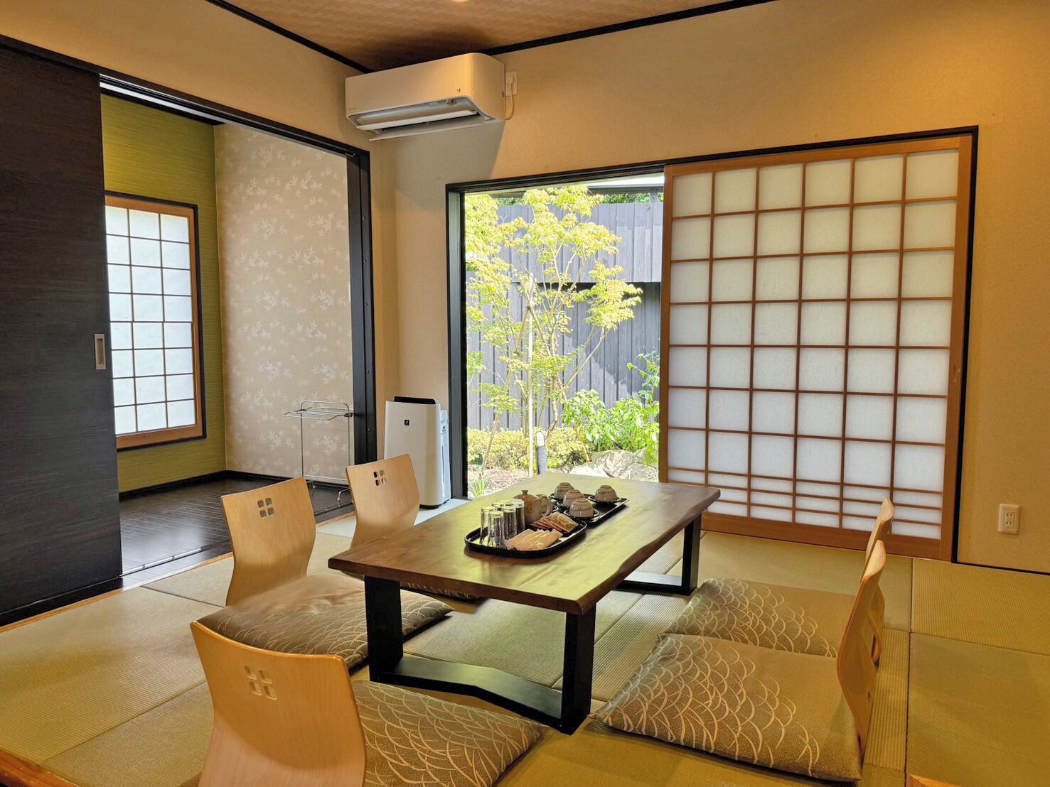 A traditional Japanese room with tatami flooring, a low table with a tray of tea, and shoji screens.