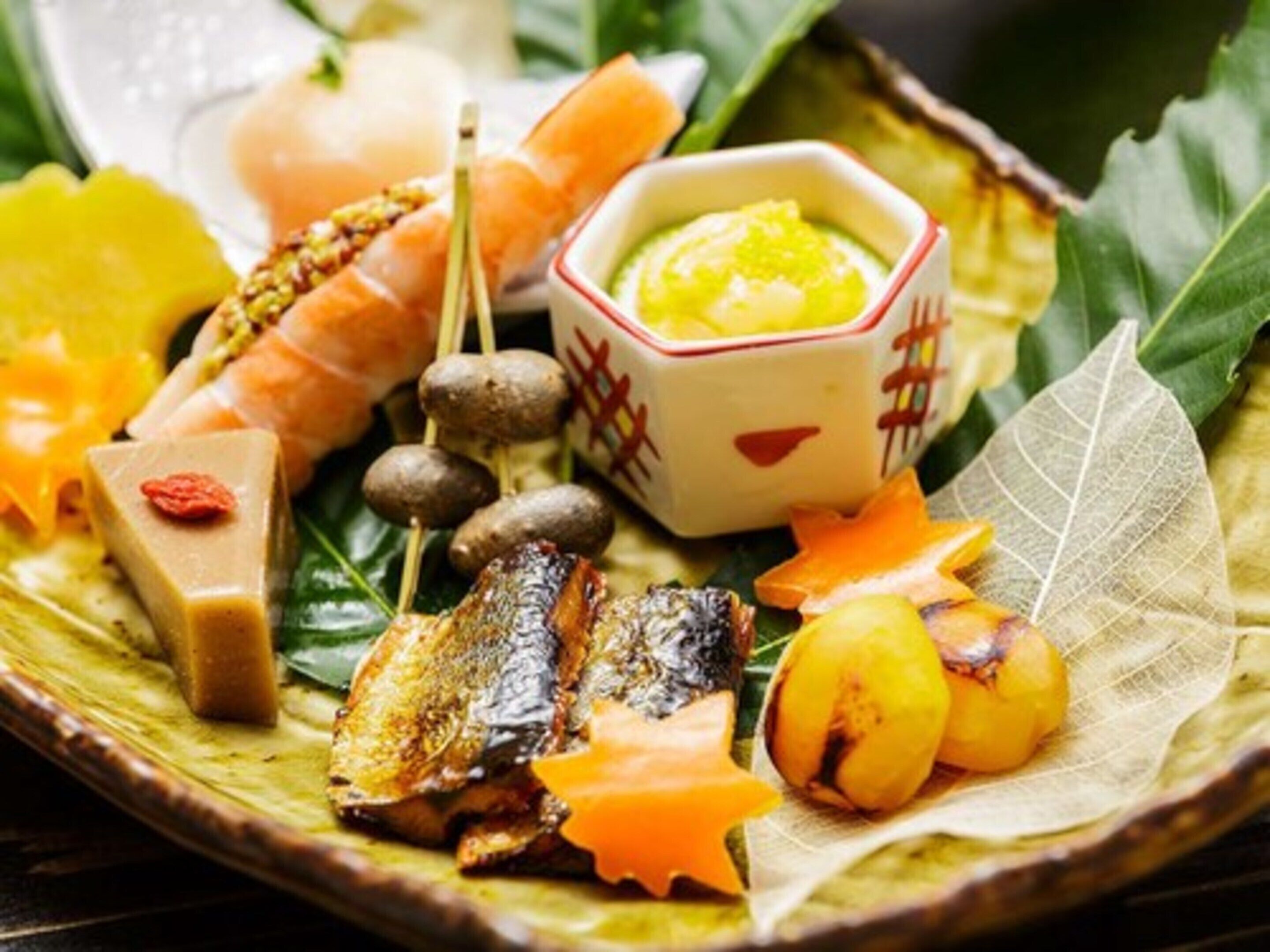 Diversos alimentos, como pescado a la parrilla, camarones y verduras, en un plato decorativo.