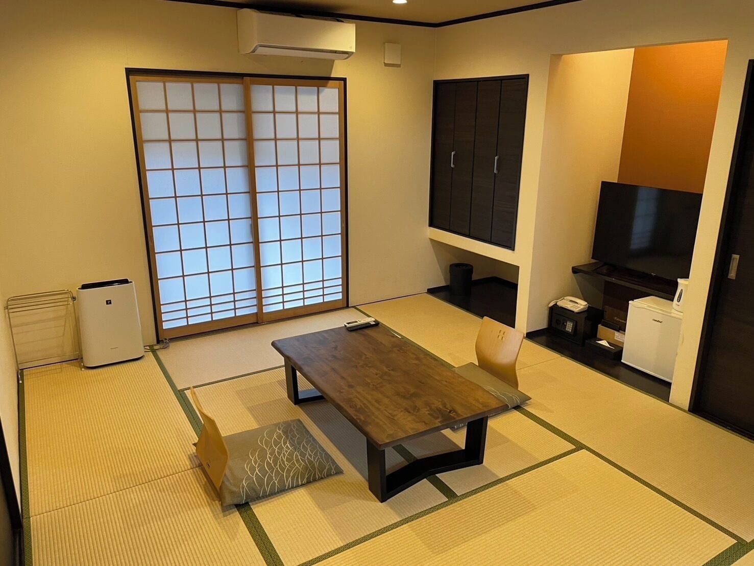 A room with tatami flooring, a low wooden table, a TV, a cabinet, and a sliding door.