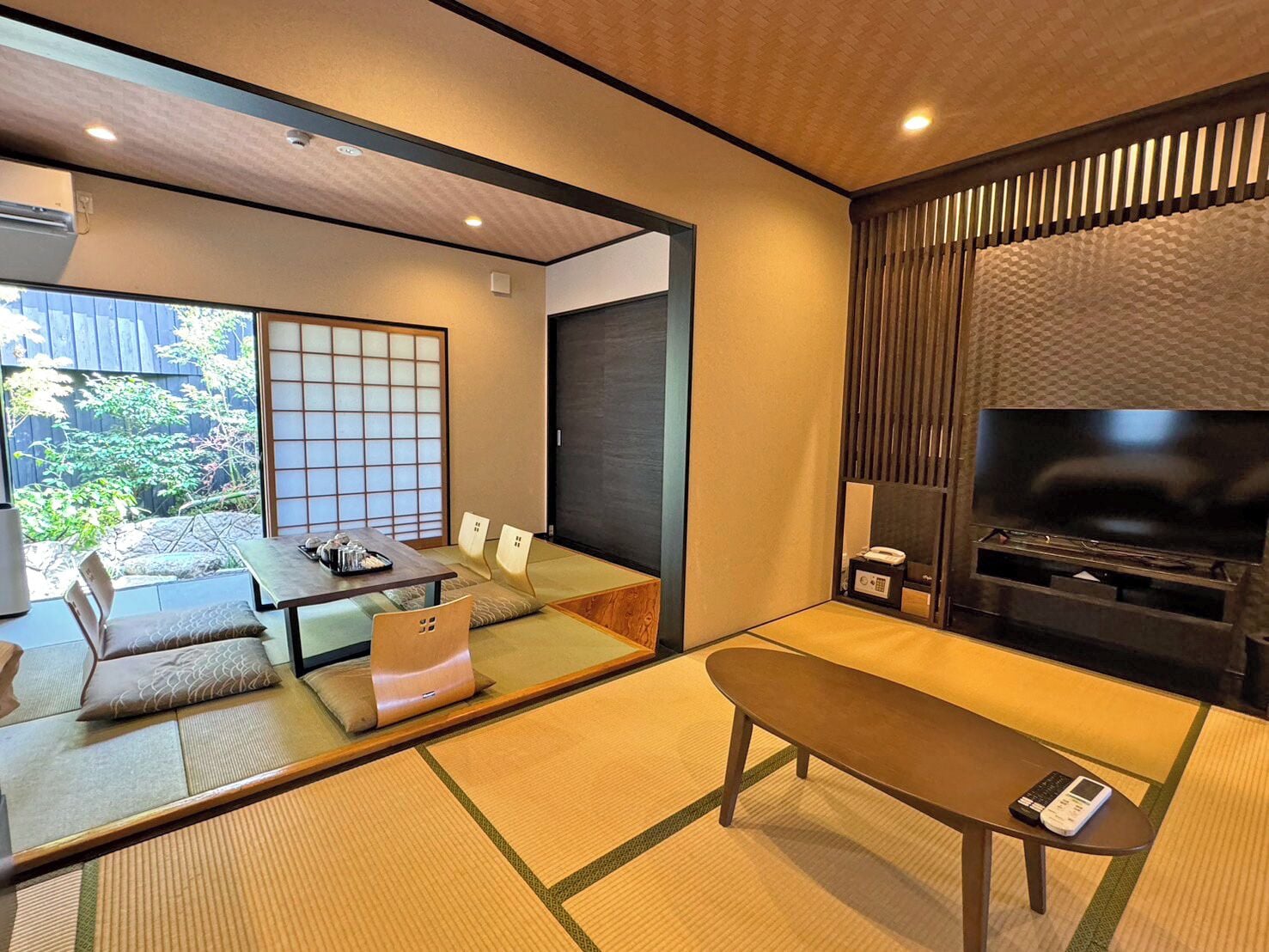 A traditional Japanese-style living room with tatami flooring, a low table, and a television.